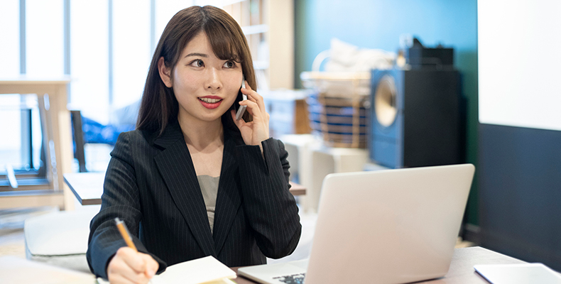請求書の電子化について取引先と電話で相談する女性